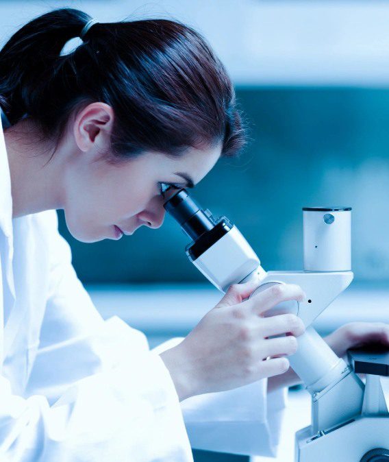 A woman looking through a microscope in a lab.